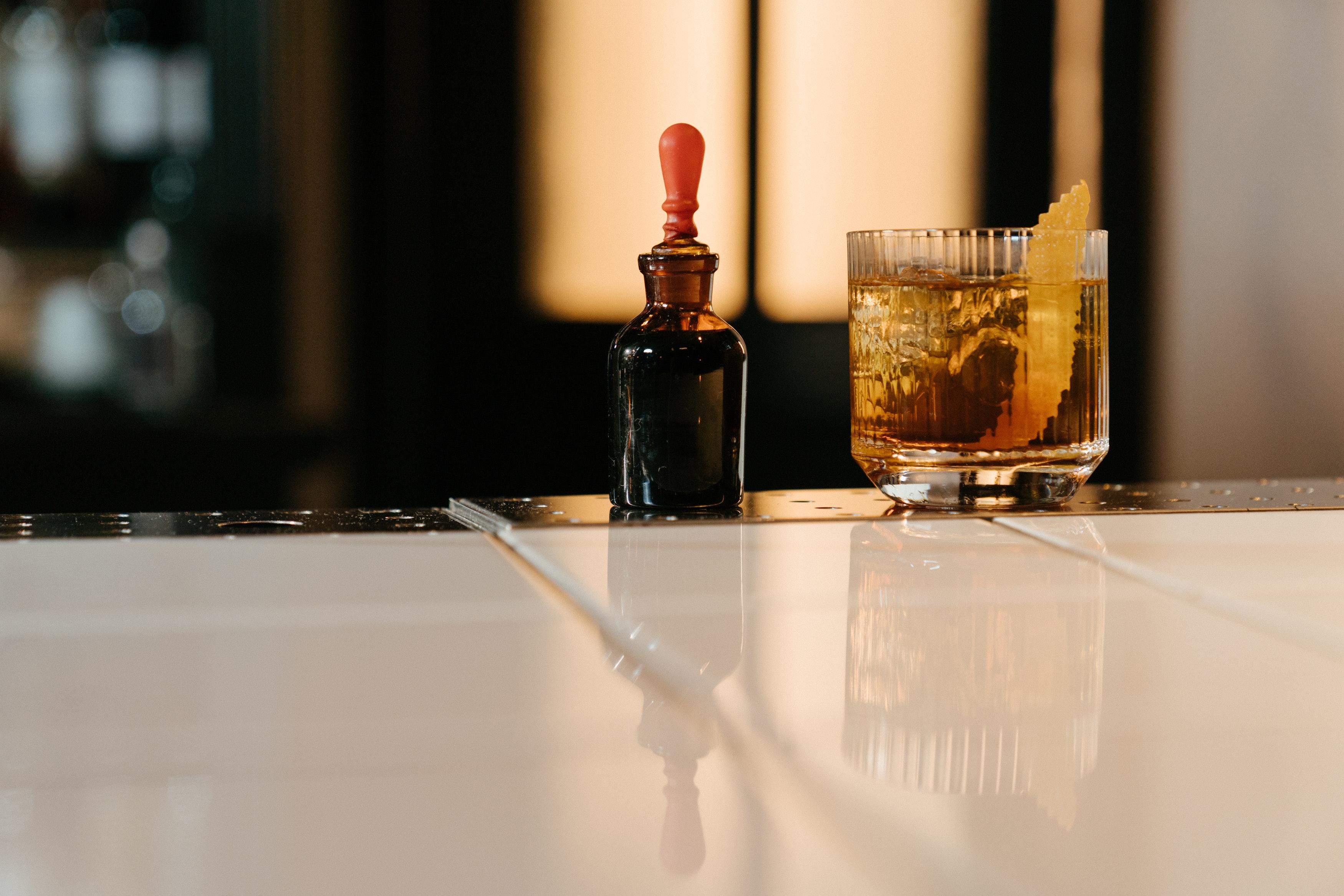 Bitters bottle next to old fashioned cocktail